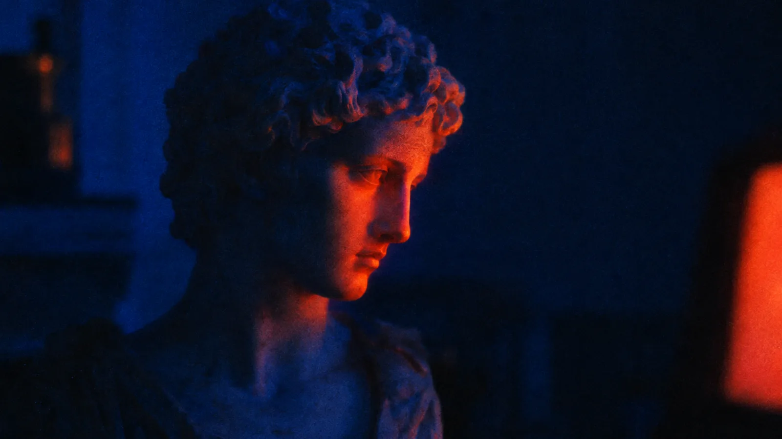 Grainy film still of a classical marble bust in a dim room lit cobalt blue, an orange-red glow on its face from a screen just out of frame